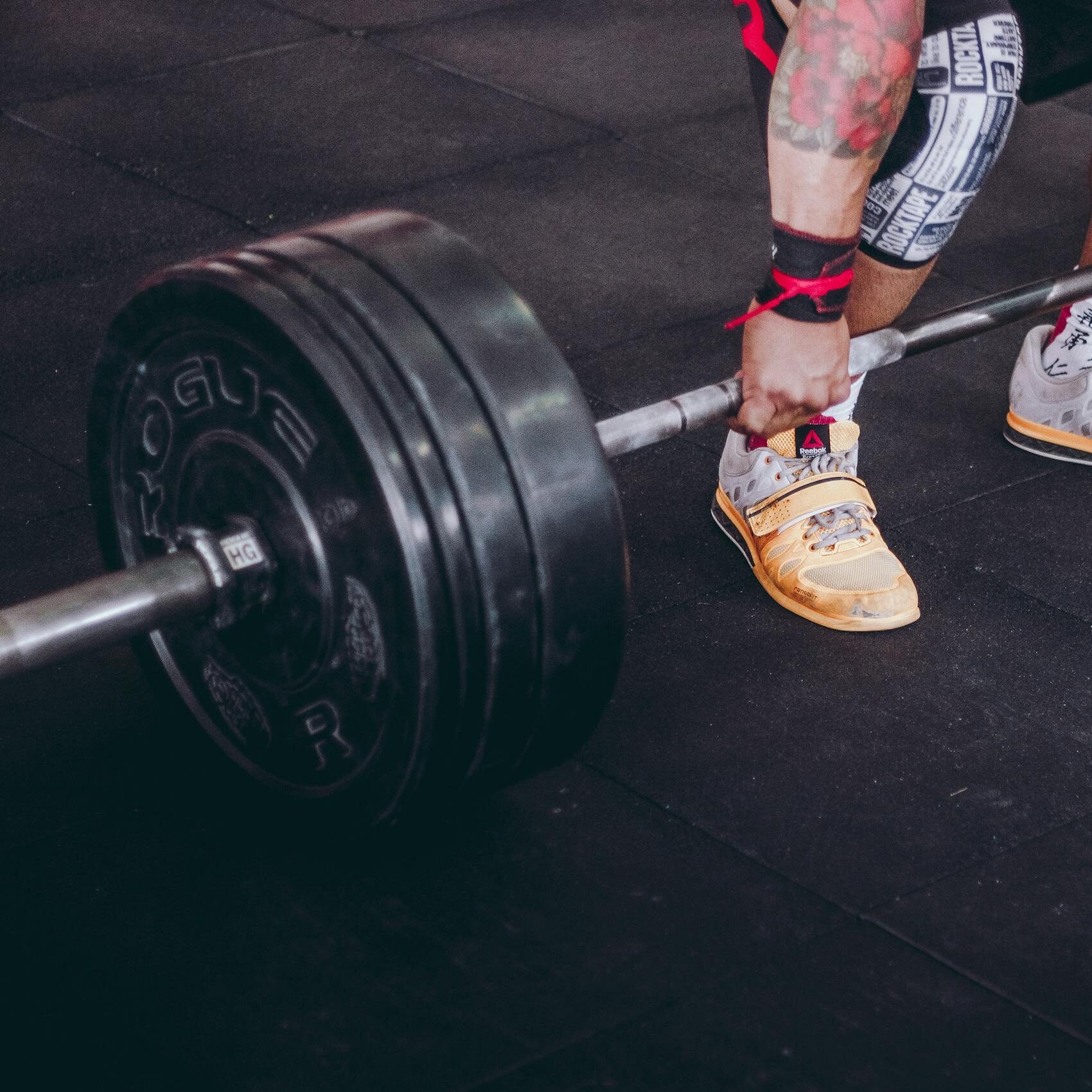 Close-up of a man performing a deadlift with a heavy barbell inside a gym. Focus on determination and strength.